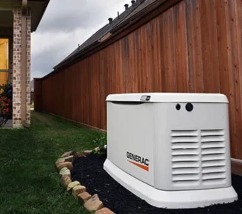 Generac standby generator set on a pad in a mulch bed alongside a home, Clark County WA