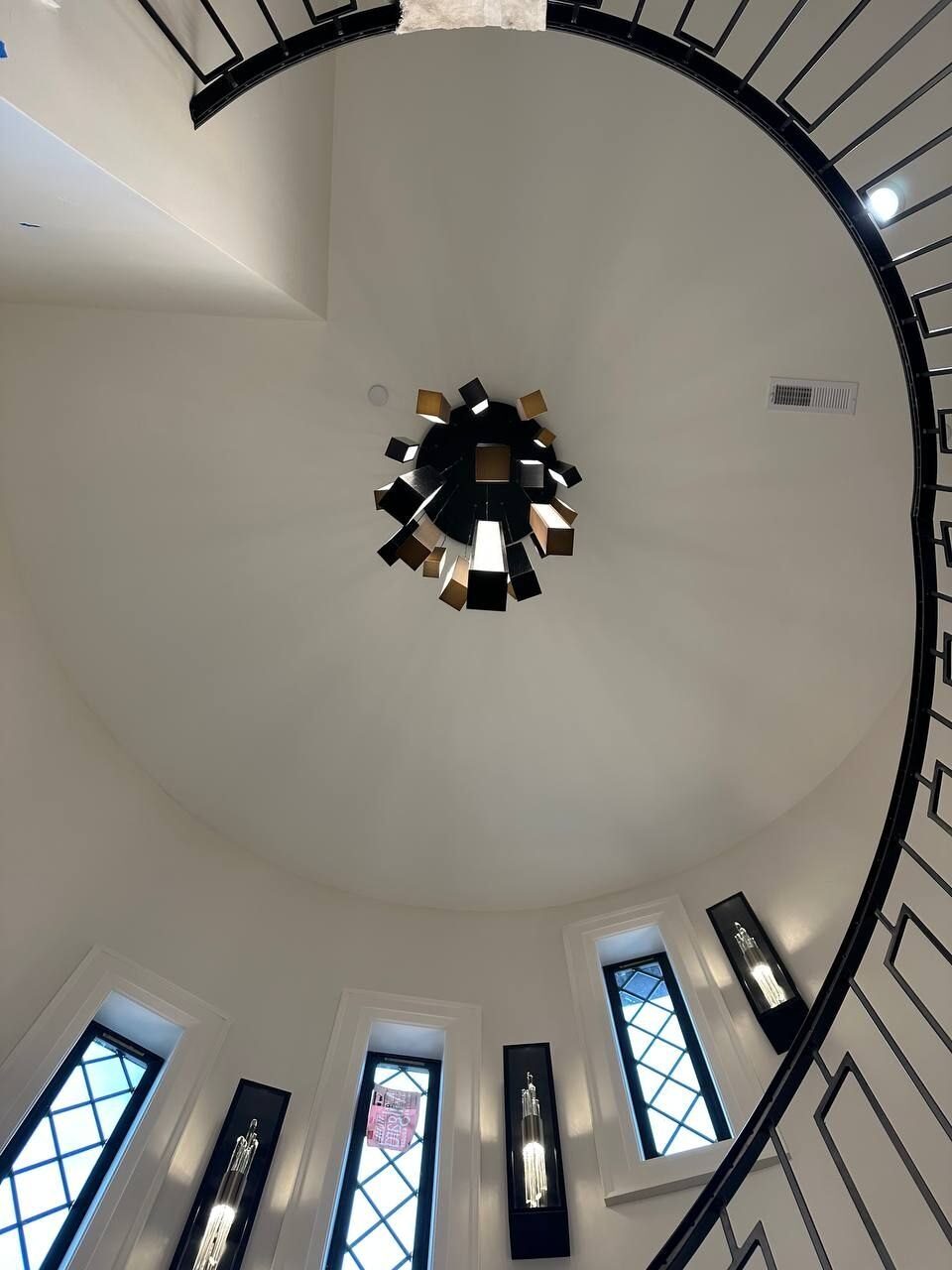 Modern chandelier above a spiral staircase with wall sconces, Vancouver WA